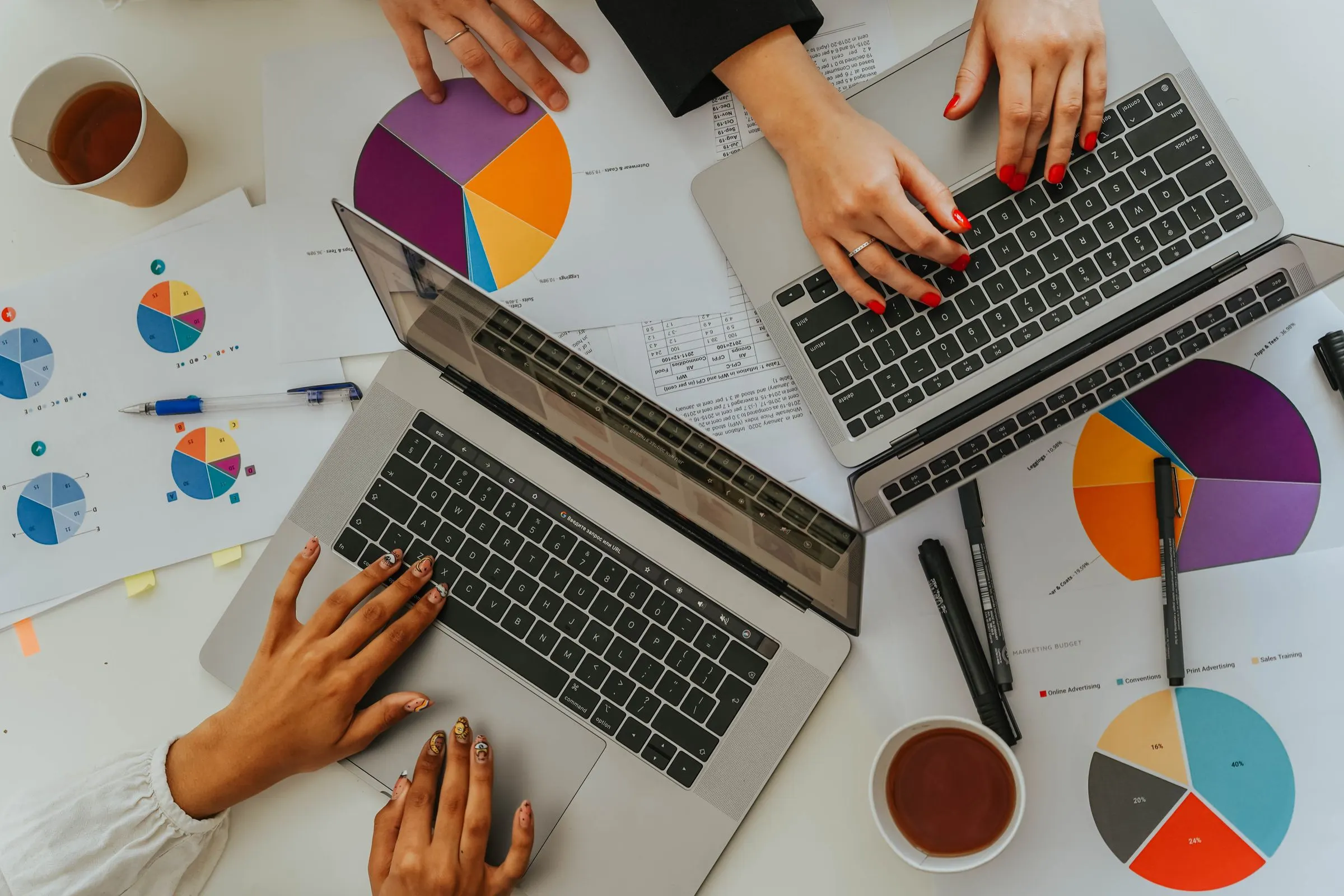 Colleagues working on laptops among printed charts