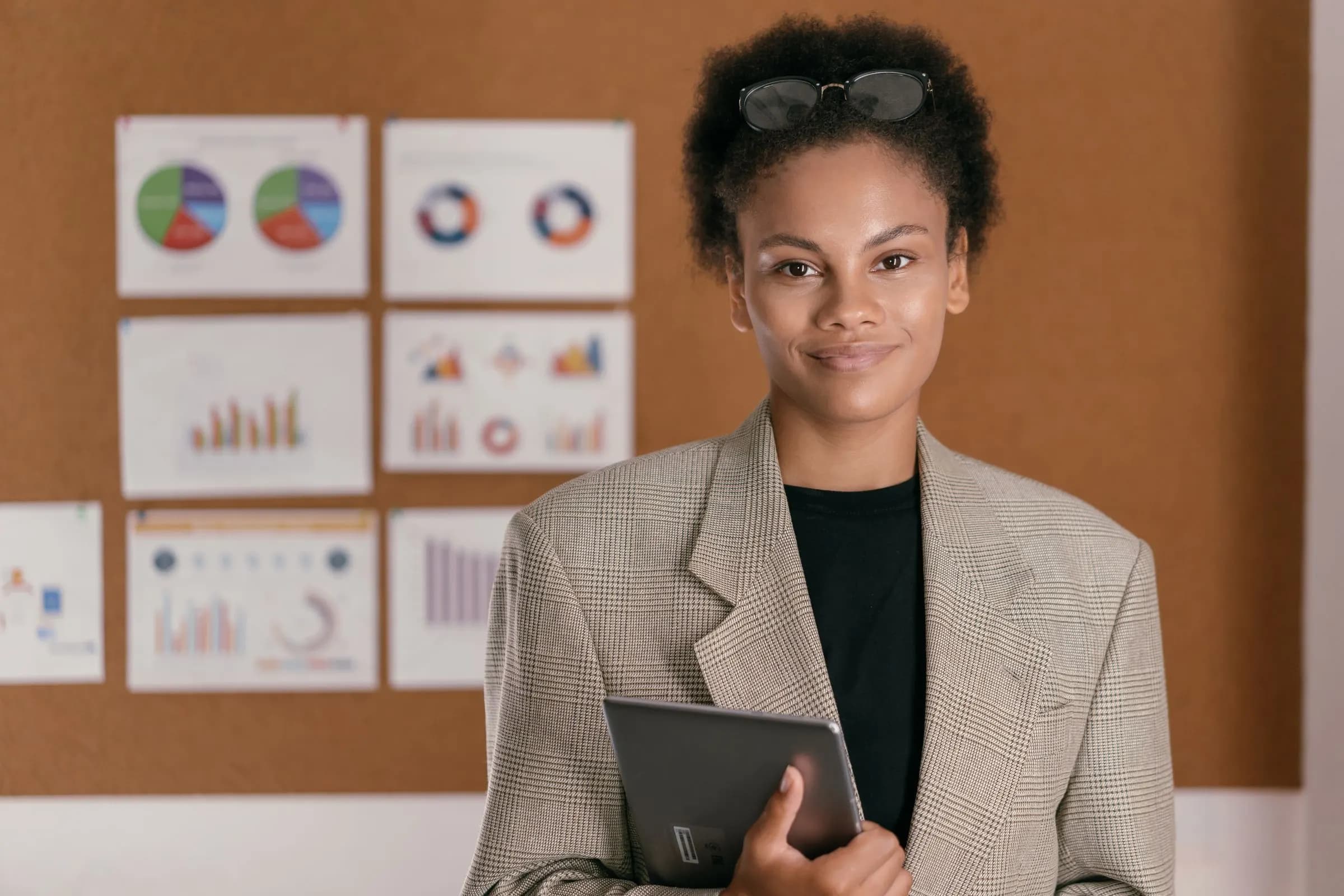 A principal holding a tablet in front of a board of charts